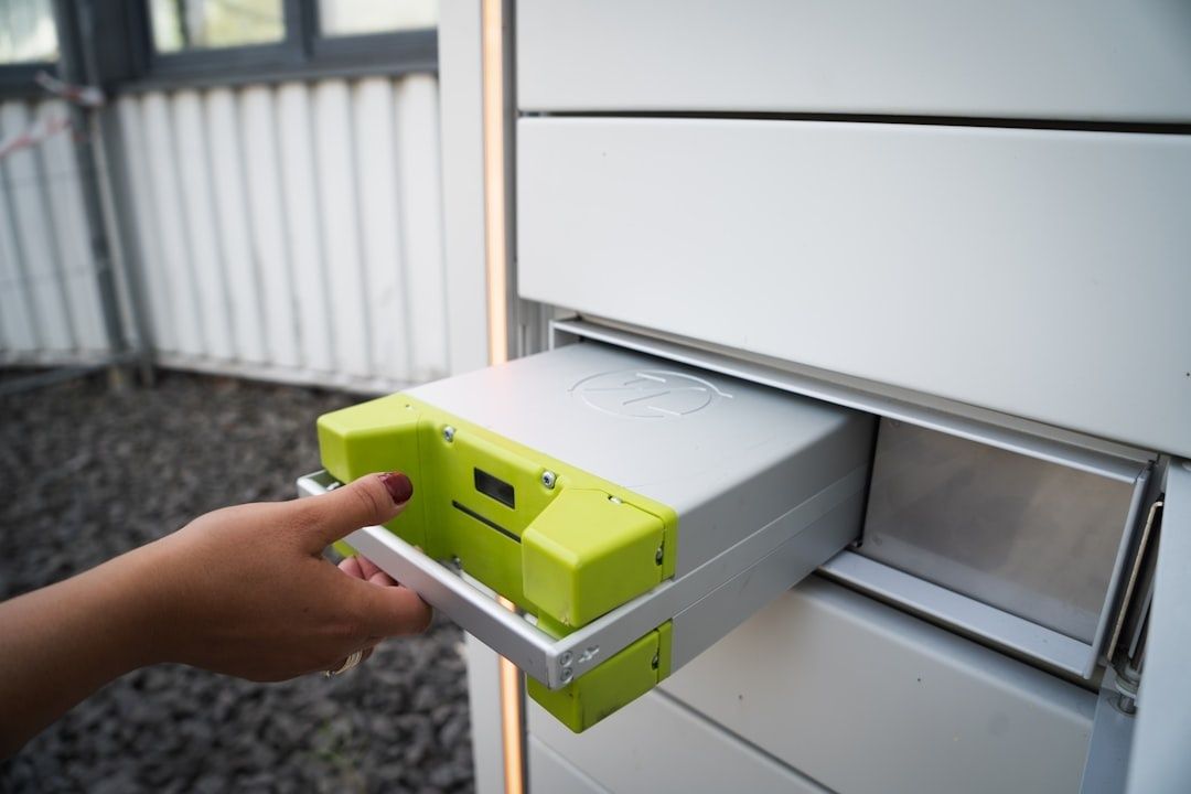En hånd skubber en kompakt energienhed ind i en vægmonteret enhed
